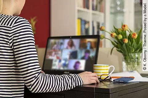Frau sitzt im Homeoffice in Onlinemeeting