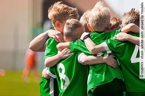 Kinder-Fußballteam. Jungs stehen in einem Kreis und umarmen sich. 
