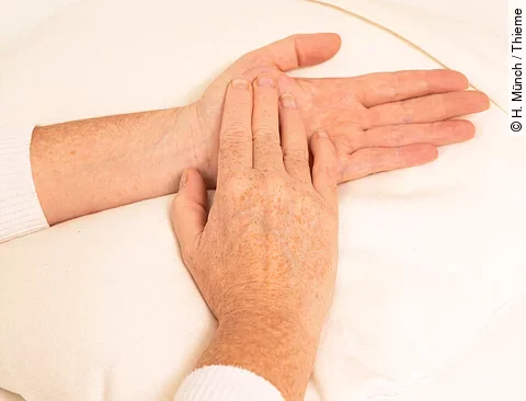 Frau massiert sich mit der rechten Hand den linken Daumenmuskel