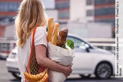 Frau mit Einkaufstüten auf einem Parkplatz