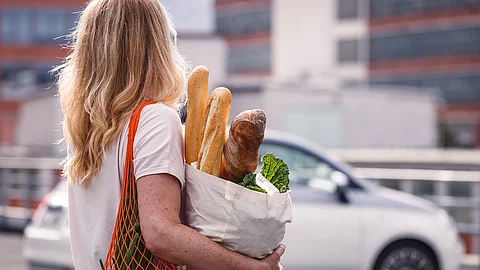 Frau mit Einkaufstüten auf einem Parkplatz