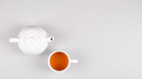 Tea cup composition on gray background. Flat lay. Eine weiße Teekanne mit Teetasse vor hellem Hintergrund