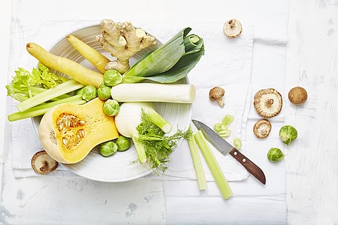 Ingwer, Rosenkohl, Lauch, Papaya auf einem Teller, arrangiert auf einem weißen Leinentuch