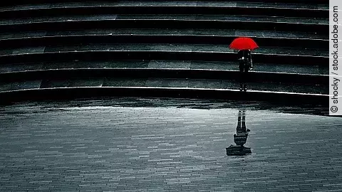 Mensch mit rotem Schirm bei Regen allein auf einer Treppe, Einsamkeit