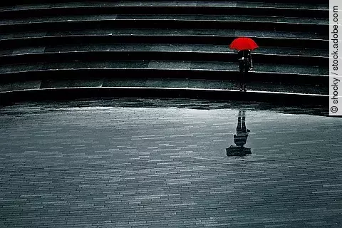 Mensch mit rotem Schirm bei Regen allein auf einer Treppe, Einsamkeit