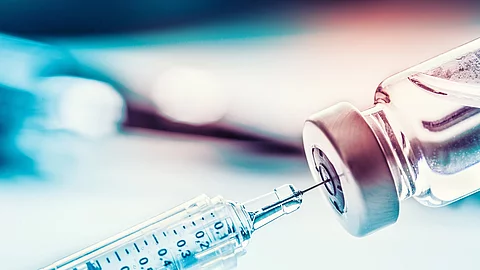 Close-up medical syringe with a vaccine Spritze sticht in Impfstoffampulle