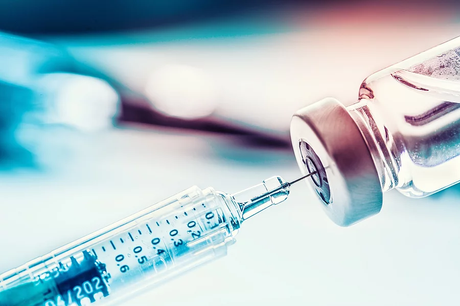 Close-up medical syringe with a vaccine Spritze sticht in Impfstoffampulle