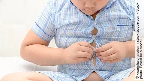Kind mit Übergewicht, welches sein Hemd nicht schließen kann. 