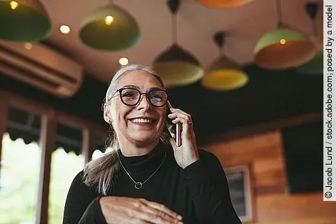Frau telefoniert mit dem Handy in einem Cafe