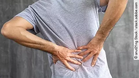 Mann von hinten, hält sich mit beiden Händen den unteren Rücken