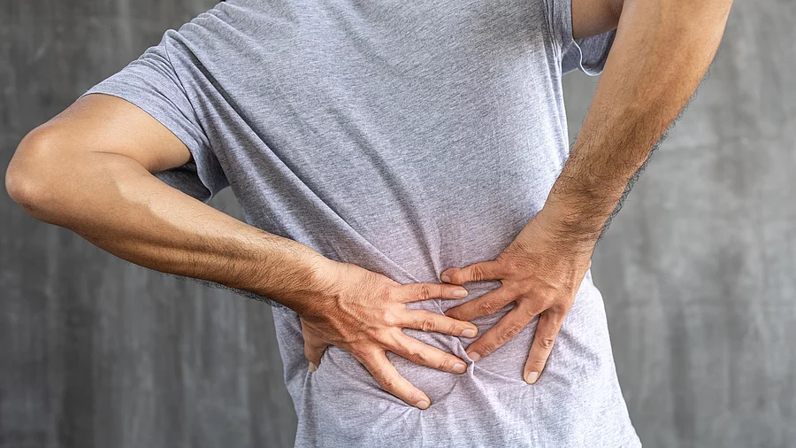 Mann von hinten, hält sich mit beiden Händen den unteren Rücken