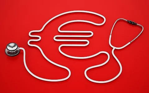 Stethoskop als Euro-Zeichen gelegt auf rotem Hintergrund