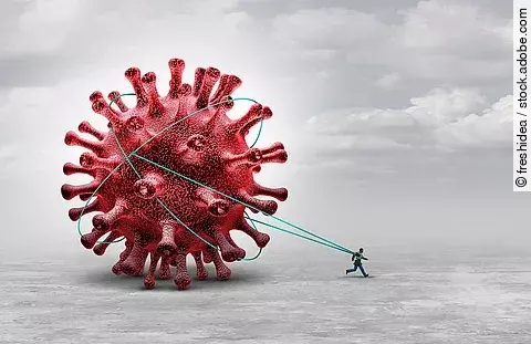 Symbolbild Long Covid: Ein Mensch zieht riesiges Coronavirus hinter sich her