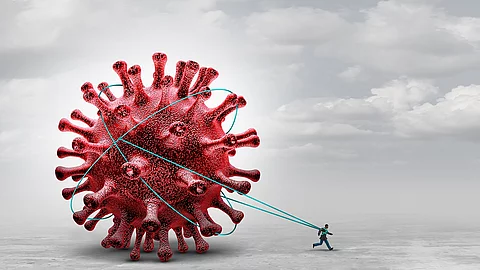 Symbolbild Long Covid: Ein Mensch zieht riesiges Coronavirus hinter sich her