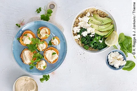 Ballaststoffreiche Speisen auf Tellern: Hummus, Süßkartoffel, Quinoa mit Spinat, Melone und Schafskäse
