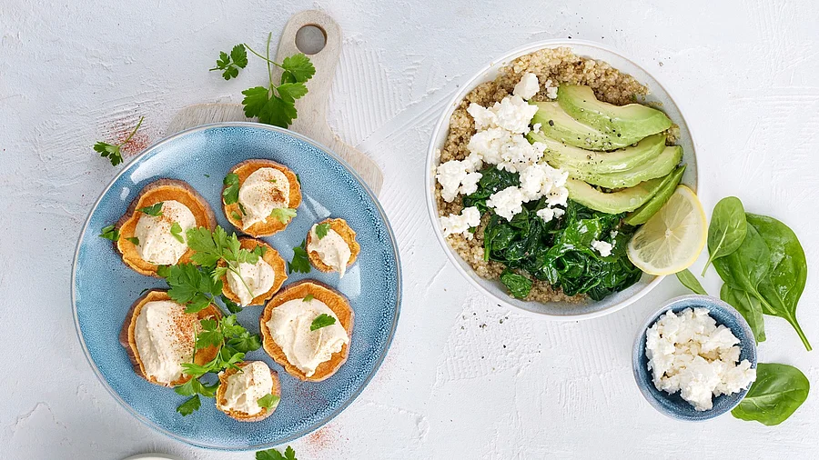 Ballaststoffreiche Speisen auf Tellern: Süßkartoffel, Quinoa mit Spinat, Melone und Schafskäse