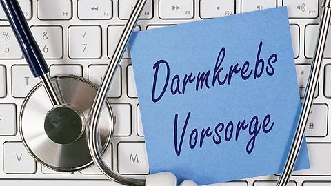 Symbolbild Darmkrebs-Vorsorge, Stethoskop, Tastatur und blauer Zettel mit Schriftzug Damkrebs Vorsorge