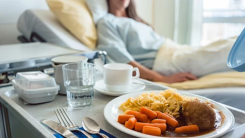 Patientenbett und Nachttisch mit Krankenhausessen