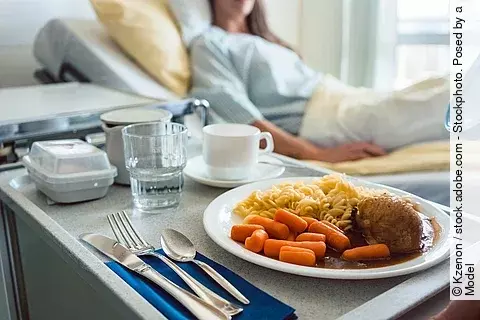 Patientenbett und Nachttisch mit Krankenhausessen