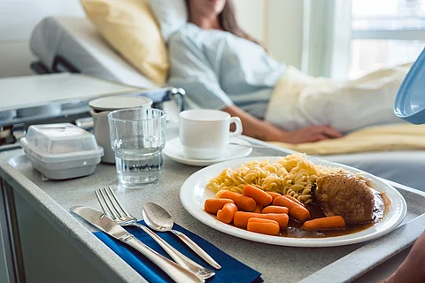 Patientenbett und Nachttisch mit Krankenhausessen
