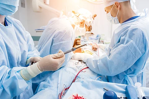 Chirurgischer Eingriff an der Wirbelsäule: 3 Ärzte stehen am OP-Tisch.