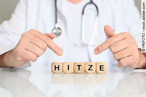 Arzt zeigt auf Holzklötzchen mit den Buchstaben HITZE