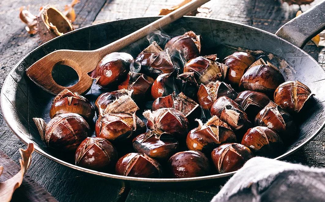Esskastanien in der Pfanne gebraten mit einem Pfannenwender aus Holz