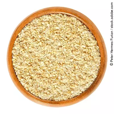 Gomashio in wooden bowl, also called gomasio. Dry condiment, made of toasted sesame seeds and salt, used in Japanese cuisine to sprinkle it over rice. Macro food photo closeup from above over white. Gomasio in einer Holzschale
