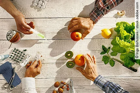 4 Hände mit Tabletten, Mandarinen, Spritzen und Nüssen.