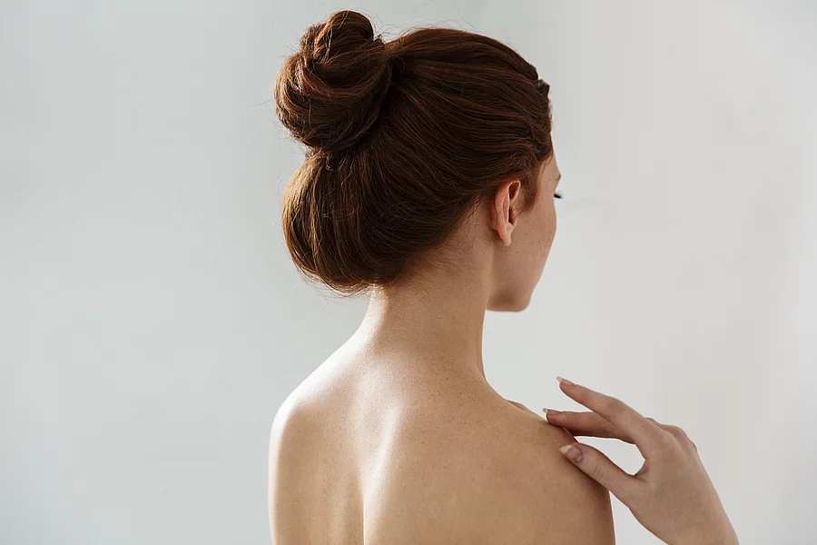 Beauty Portrait von einer jungen Frau mit hochgebundenen Haaren (Rückenansicht).