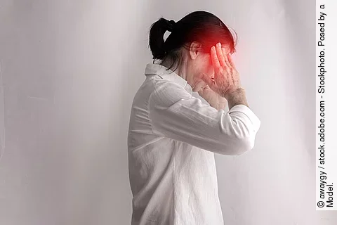 Frau mit Kopfschmerz hat die Hände an den Schläfen