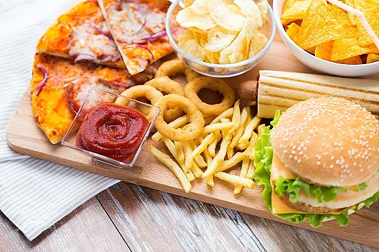 Fast Food auf einem Tisch: Burger, Pommes, Zwiebelringe, Pizza.