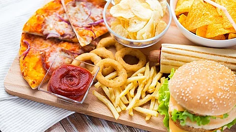 Fast Food auf einem Tisch: Burger, Pommes, Zwiebelringe, Pizza.