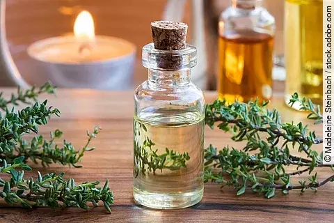 Thymianzweige und Fläschchen mit ätherischem Öl