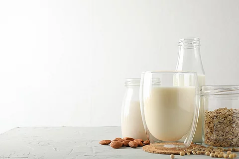 Glasflasche und Glas mit Milch, daneben Haferflocken und Mandeln