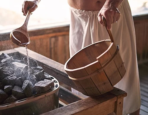 Ein Mann macht einen Aufguss in einer Sauna.