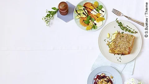 Drei Teller mit verschiedenen Gerichten, Besteck und Pfeffermühle rechts außen im Bild platziert. 