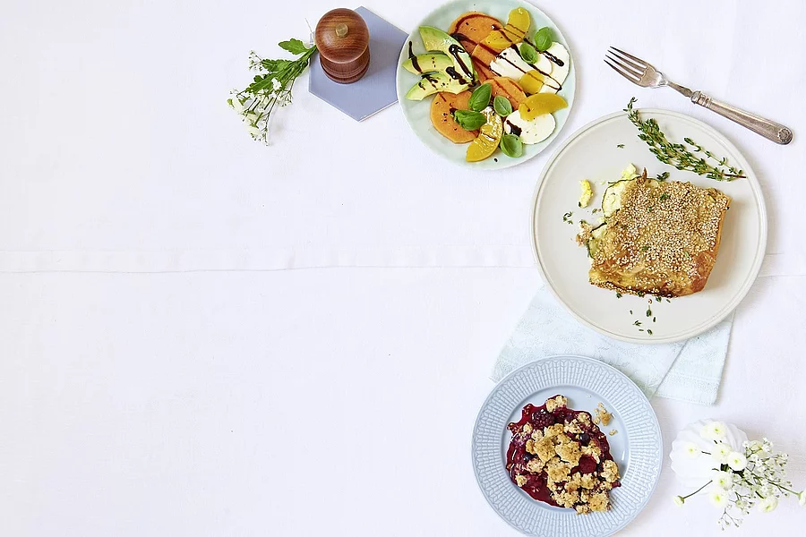 Drei Teller mit verschiedenen Gerichten, Besteck und Pfeffermühle rechts außen im Bild platziert. 