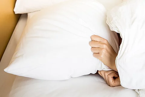 Frau im Bett, Kopfkissen über dem Kopf