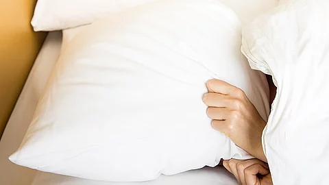 Frau Bett aufstehen wecken strecken Frau im Bett, Kopfkissen über dem Kopf