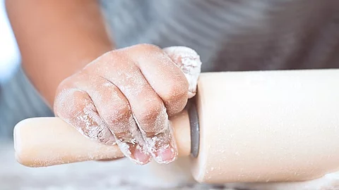 Little child girl hands prepares a dough for baking cookies in t Kinderhände beim Teig ausrollen