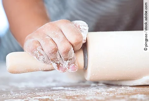 Kinderhände beim Teig ausrollen