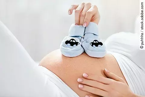 Schwangerer Bauch mit Babyschuhen