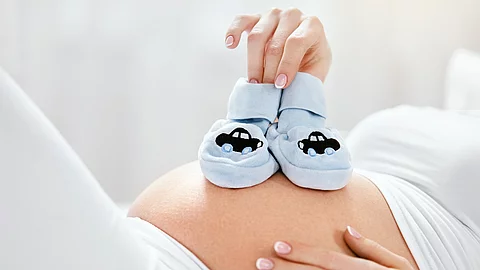 Pregnancy. Pregnant Belly With Little Baby Shoes Schwangerer Bauch mit Babyschuhen