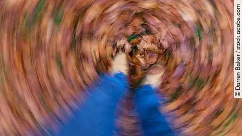 Symbolbild Schwindel: Frau steht in Herbstlaub, alles dreht sich 
