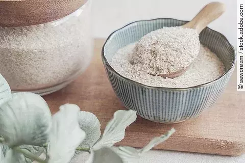 Flohsamenschalen in einer Schale mit Holzlöffel