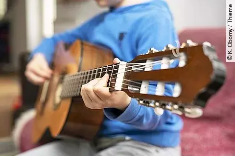 Ein Kind spielt Gitarre.