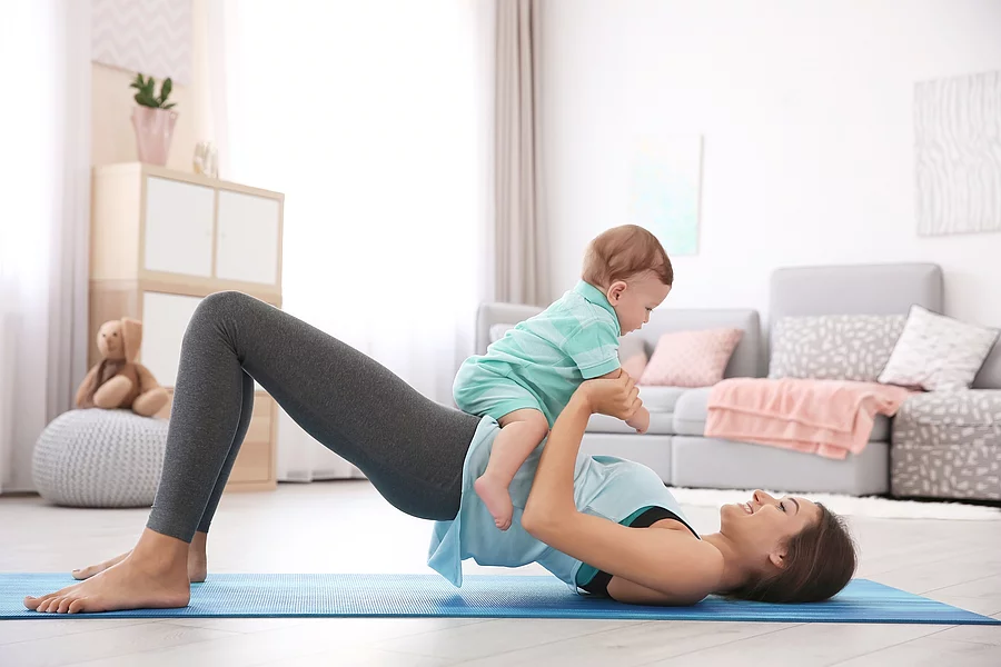 Young mother doing yoga with baby at home Junge Mutter macht Yoga mit Baby auf dem Bauch liegend