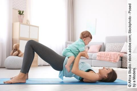Junge Mutter macht Yoga mit Baby auf dem Bauch liegend