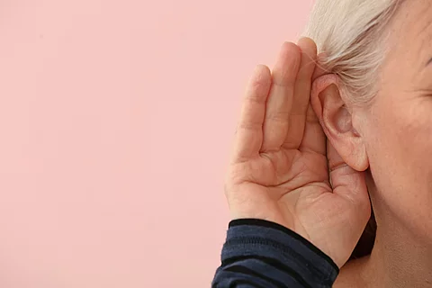 Frau hält Hand hinter Ohr und stellt ein Lauschen dar